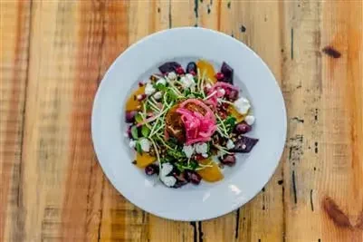 Vibrant salad with roasted beets, orange, cheese, and pickled onions.