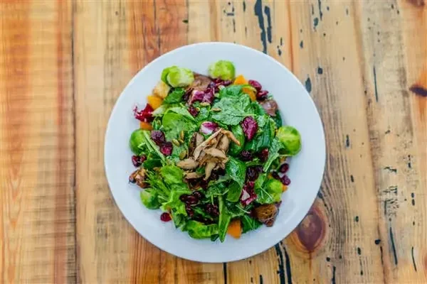 Vibrant salad with greens, Brussels sprouts, squash, cranberries, and seeds.