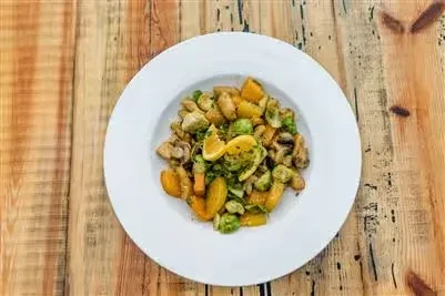 Vibrant roasted vegetable dish with Brussels sprouts, squash, and lemon slice.