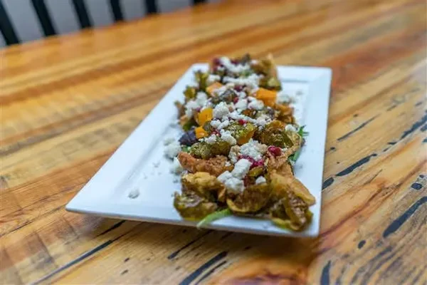 Roasted Brussels sprouts, squash, feta, and pomegranate on a white plate.