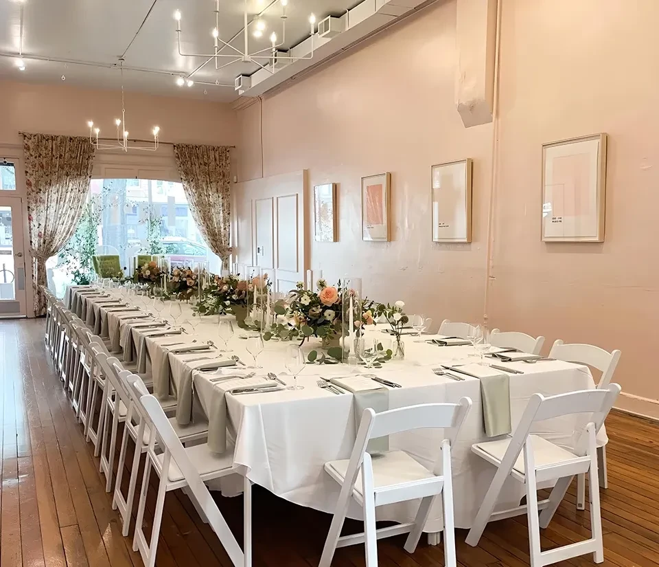 Elegantly set table with pink and white flowers in a pink room.
