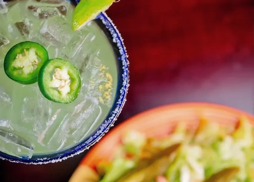 Margarita with blue-white salted rim, jalapeño, and lime slices.
