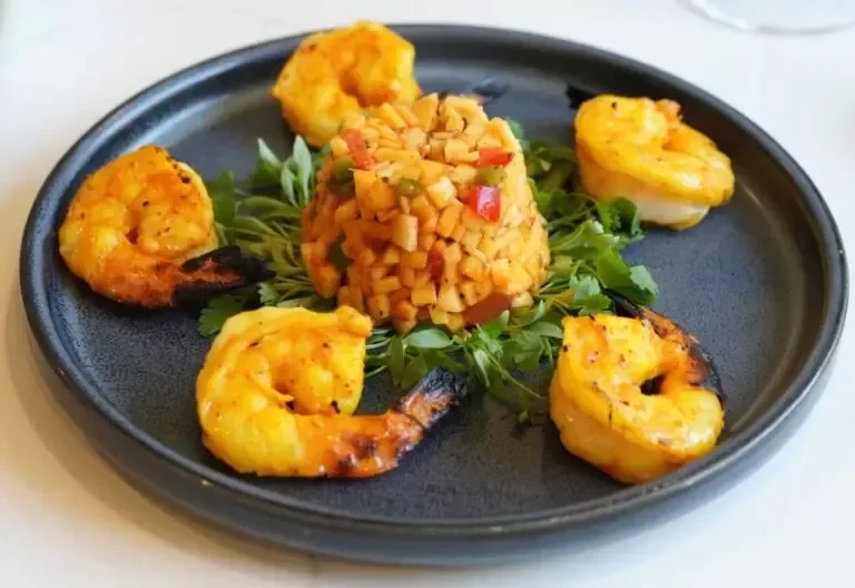 Artfully plated grilled shrimp with a colorful vegetable and herb side.
