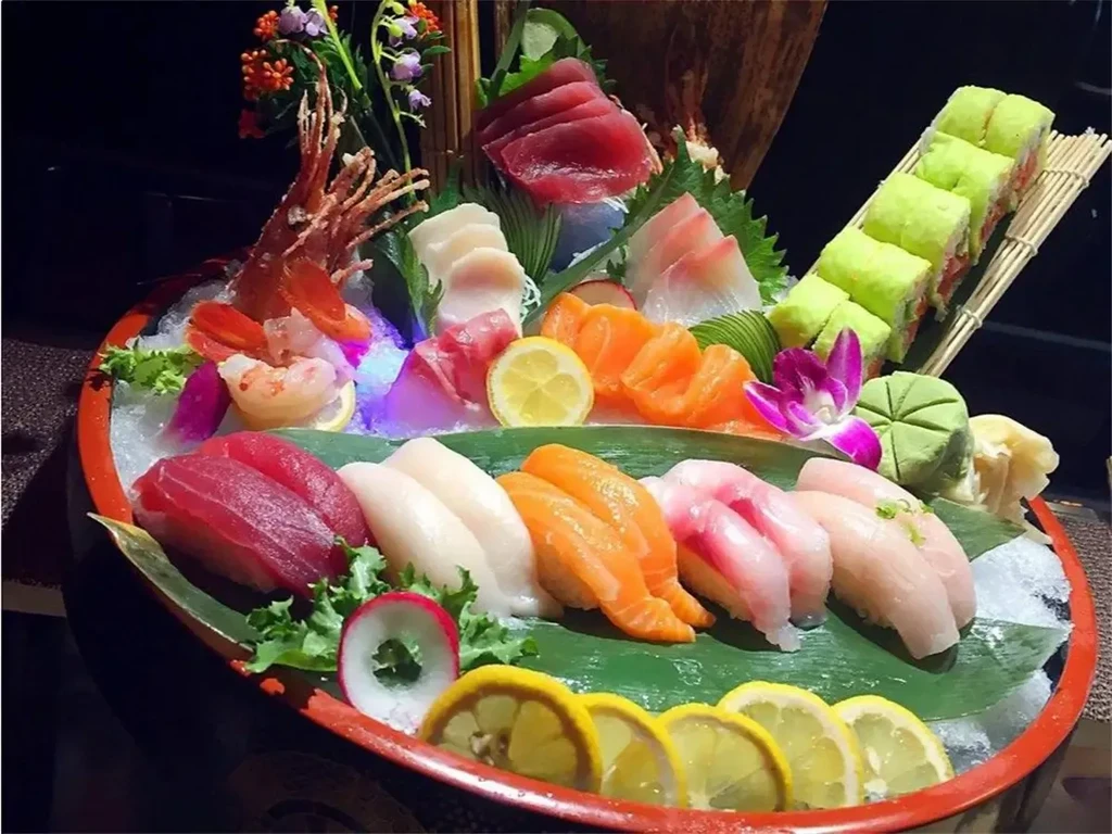 Elaborate sushi and sashimi boat with ice, prawns, and blue light.
