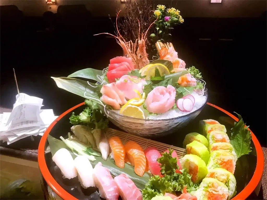 Elaborate two-tiered sushi and sashimi platter with garnishes.