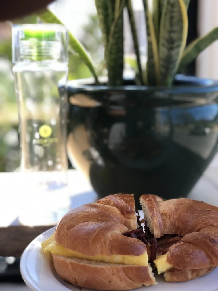 Croissant sandwich cut in half, filled with scrambled eggs and bacon.