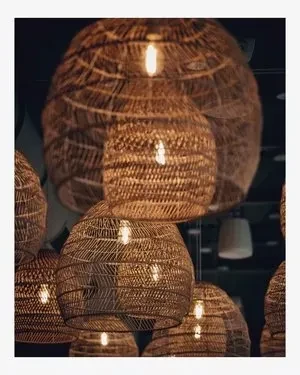 Multiple woven rattan pendant lights with a warm glow in a dark room.