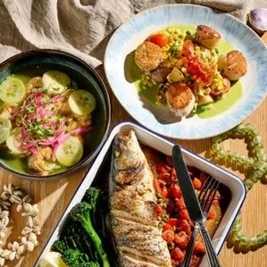 Table spread with scallops, grilled fish, and a green seafood dish.