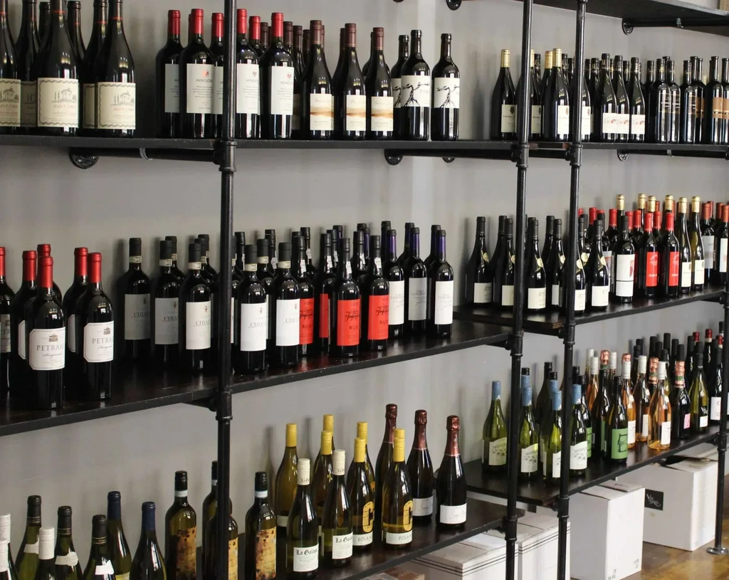 Extensive collection of red, white, and sparkling wines on industrial shelving.
