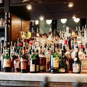 A dark wooden bar counter densely stocked with various liquor bottles.