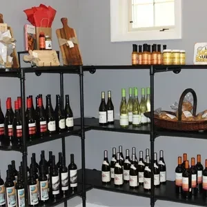 Black retail shelves stocked with wine, jars, and packaged food.