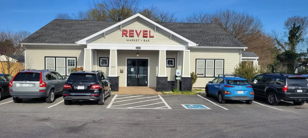 Exterior of Revel Market + Bar building with cars in parking lot.