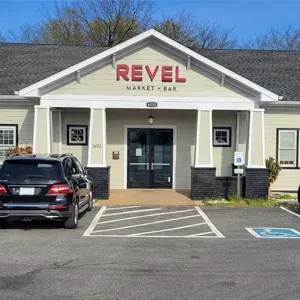 Revel Market + Bar exterior, 860, with parking lot and parked SUV.