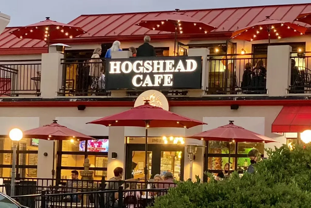 HOGSHEAD CAFE: Two-story restaurant exterior at dusk with lighted red umbrellas.