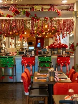 Restaurant interior lavishly adorned with red and green Christmas decorations.