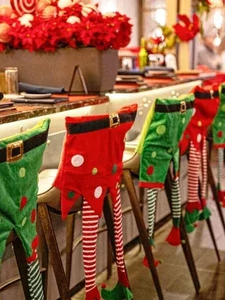 Festive bar with elf-decorated stools, poinsettias, and holiday ornaments.