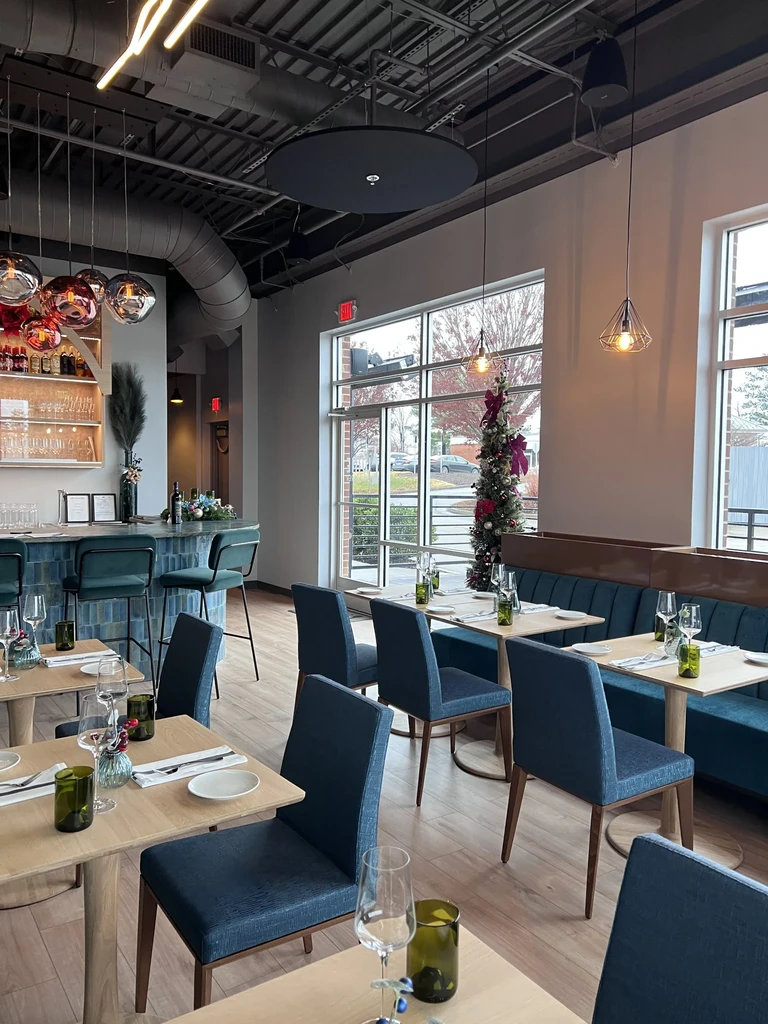 Modern restaurant interior with teal bar, dining area, and Christmas tree.