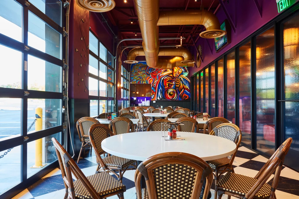 Empty restaurant interior with purple walls, checkerboard floor, and saxophone mural.