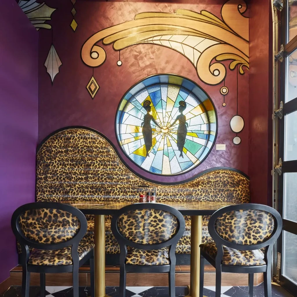 Restaurant interior with leopard print seating, art deco wall, and stained glass.