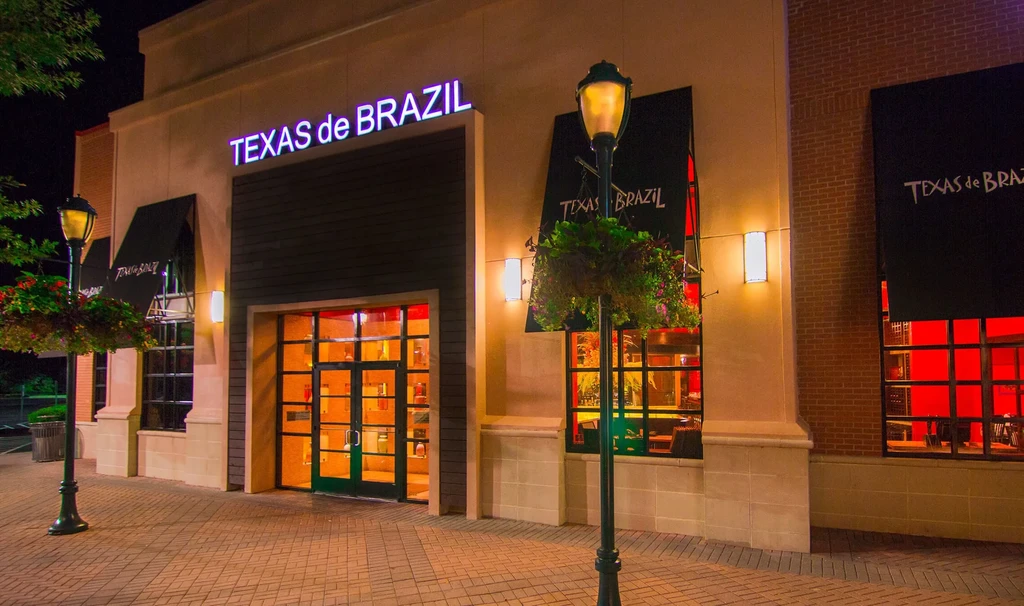 Upscale Texas de Brazil restaurant exterior, warmly lit at night.