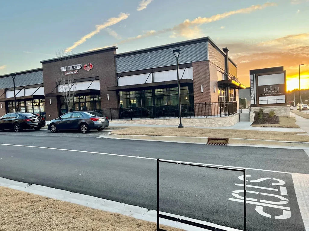 Exterior of The Twisted restaurant with crab logo at sunset.