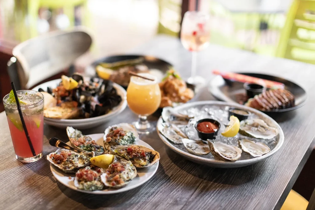 A spread of raw and baked oysters, cocktails, and other food.
