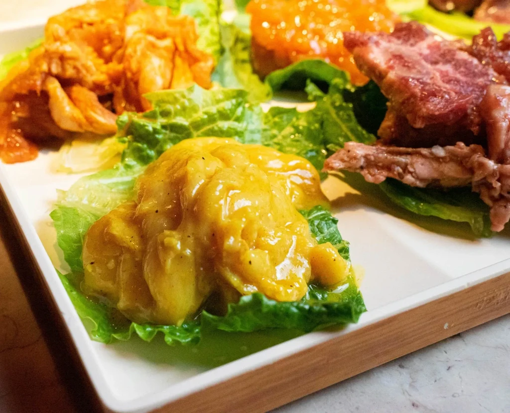 Platter with creamy yellow dip, stewed meat, and sliced rare meat.