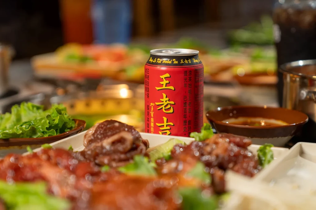 Red Wong Lo Kat tea can, meat, lettuce on an Asian restaurant table.