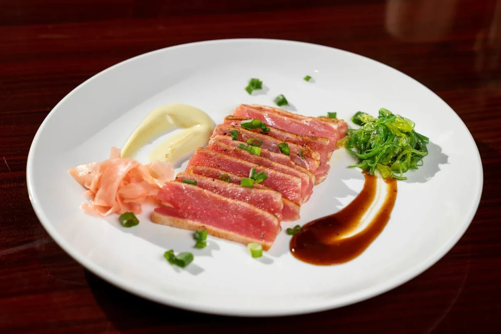 Seared tuna slices, pickled ginger, seaweed salad, green onions, and sauces.