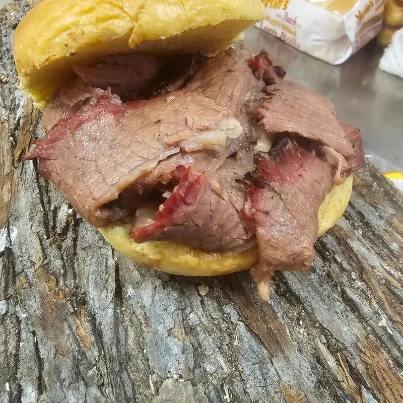 Smoked beef sandwich on a bun, on rustic wood.