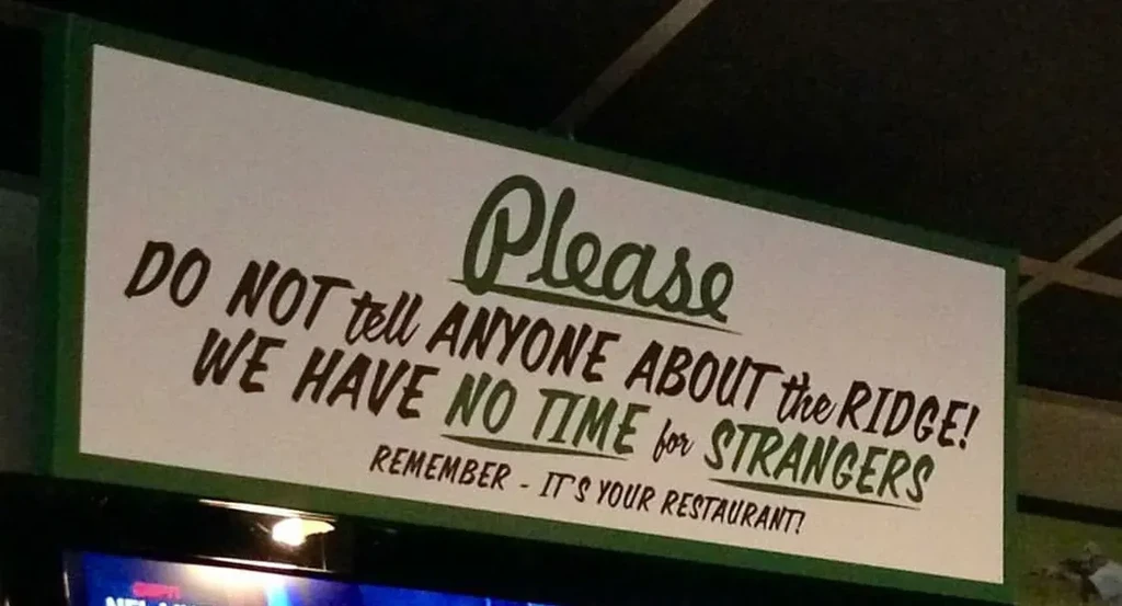 Rectangular sign warns against telling strangers about "The Ridge" restaurant.