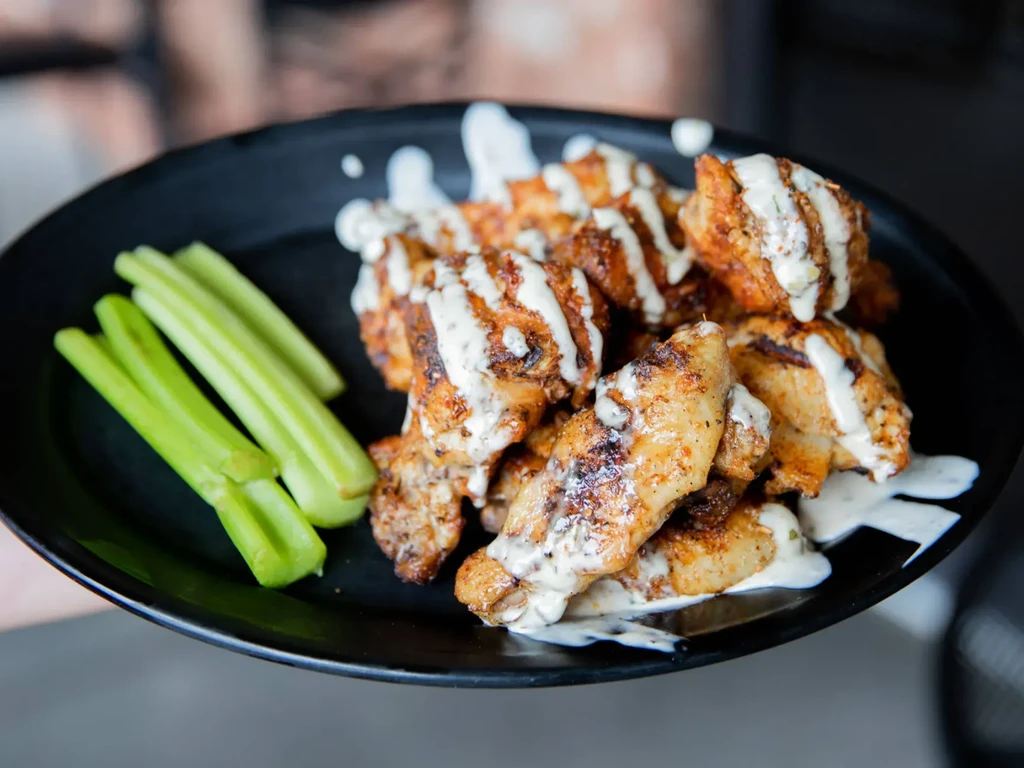 Crispy chicken wings with creamy herb sauce and celery sticks.