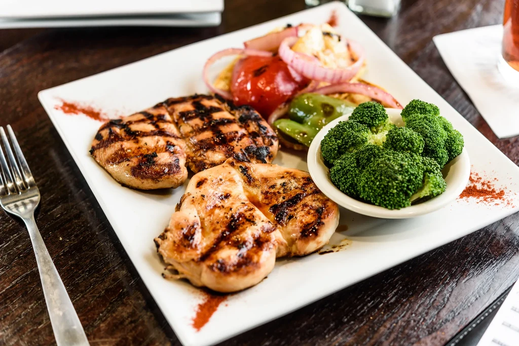 Grilled chicken breast, roasted vegetables, and steamed broccoli on plate.