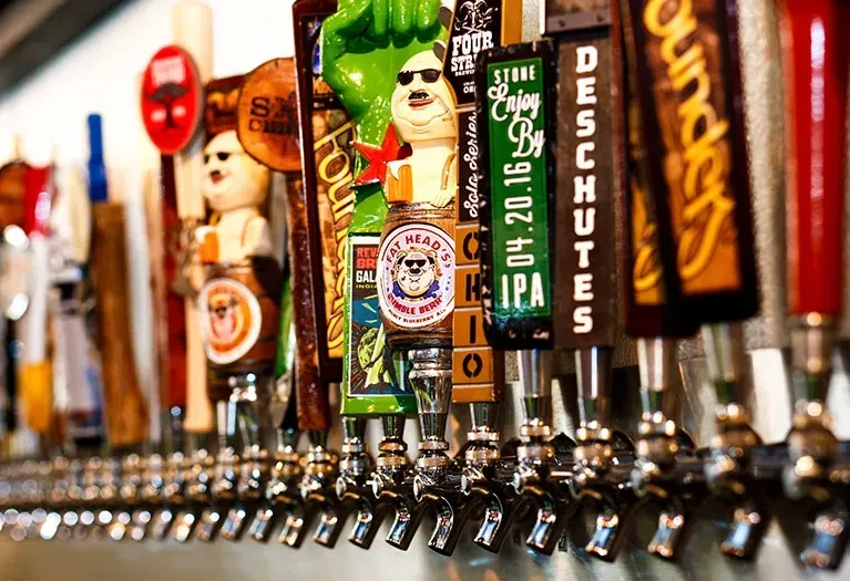Numerous gleaming craft beer tap handles with distinct branding.