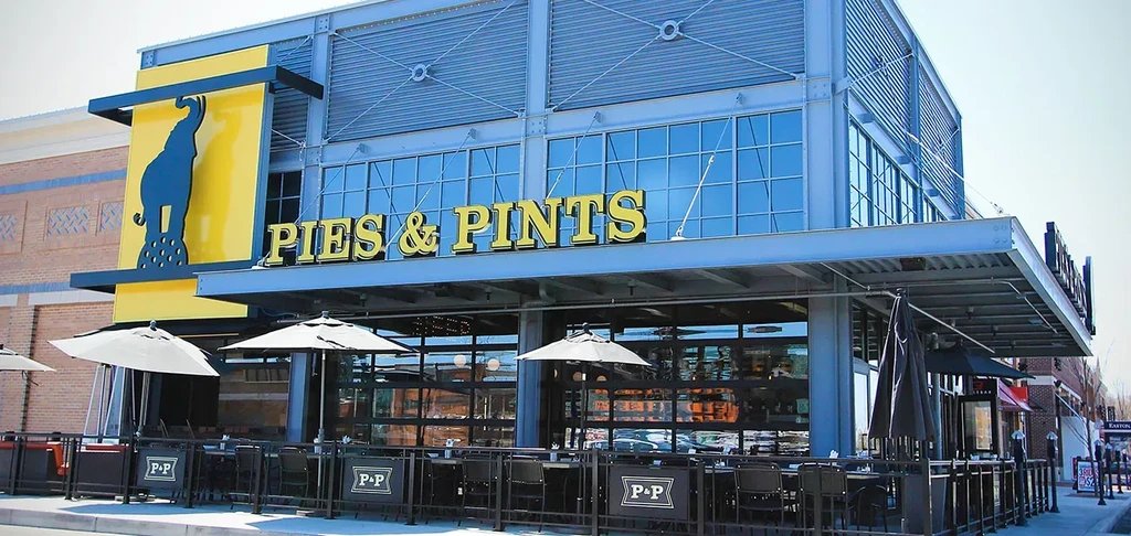 Modern "Pies & Pints" restaurant with blue steel, elephant logo, and patio.