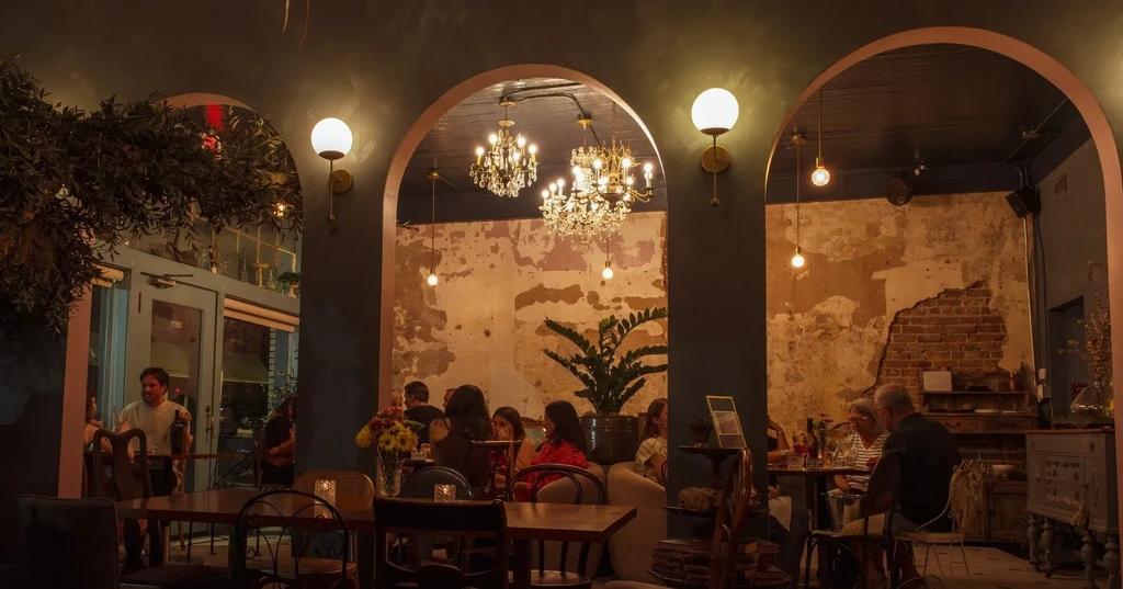 Dimly lit rustic restaurant interior with arched openings and dining patrons.