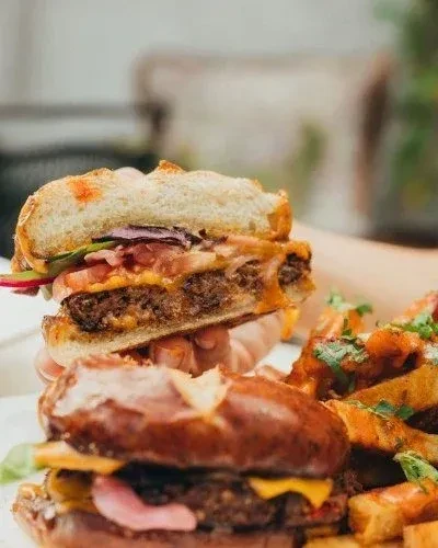 Two burgers and fries, one held, showing its internal layers.