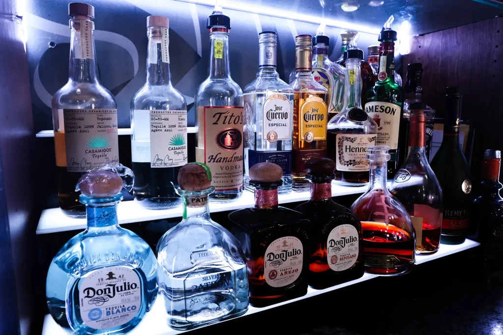 Vibrant, backlit liquor bottles displayed on modern bar shelves.