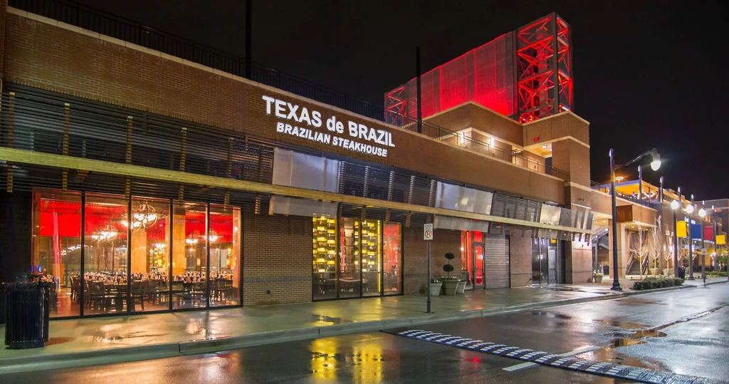 Texas de Brazil steakhouse exterior at night, reflecting on wet street.