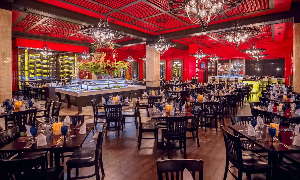 Elegant red-walled restaurant interior, buffet, wine wall, and chandeliers.