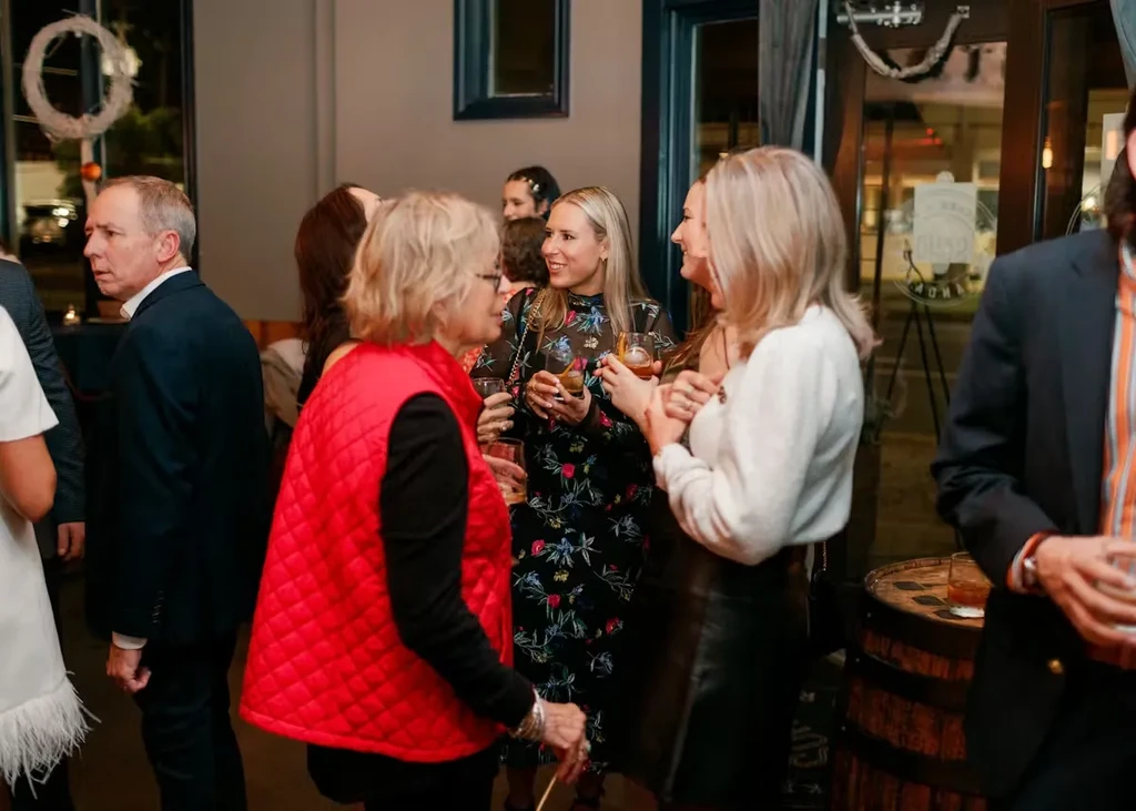 People converse and drink at a lively evening bar gathering.