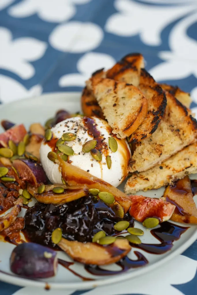 Plated burrata with figs, pear, grilled bread, and balsamic glaze.