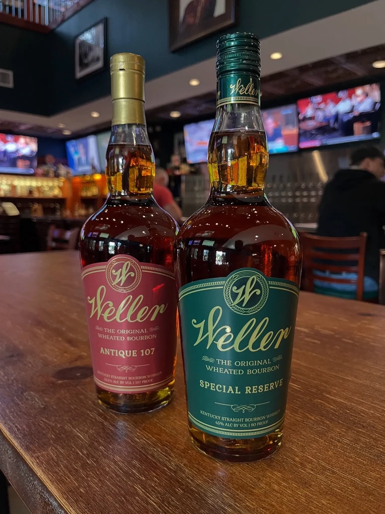 Weller Antique 107 and Special Reserve bourbon bottles on a bar.