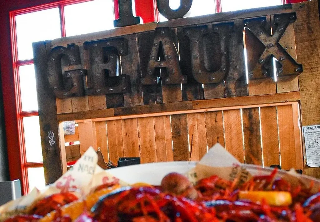 Blurred crawfish boil platter, rustic restaurant background with "GEAUX" sign.