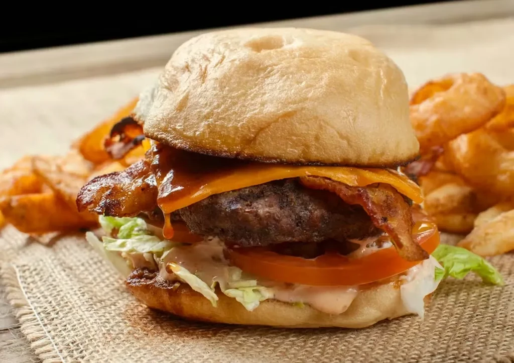 Gourmet burger with melted cheese, crispy bacon, lettuce, tomato, and fries.