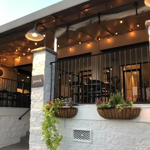 Multi-level outdoor patio with stone wall, planters, string lights, and seating.