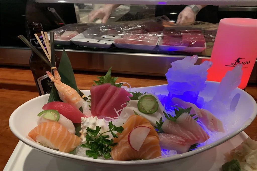 Elaborate sushi and sashimi platter on blue LED-lit ice in a restaurant.