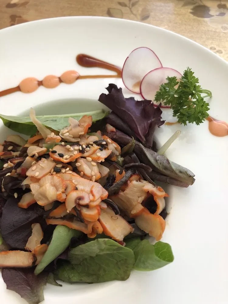 Colorful seafood salad with mixed greens, radish, and decorative sauces.