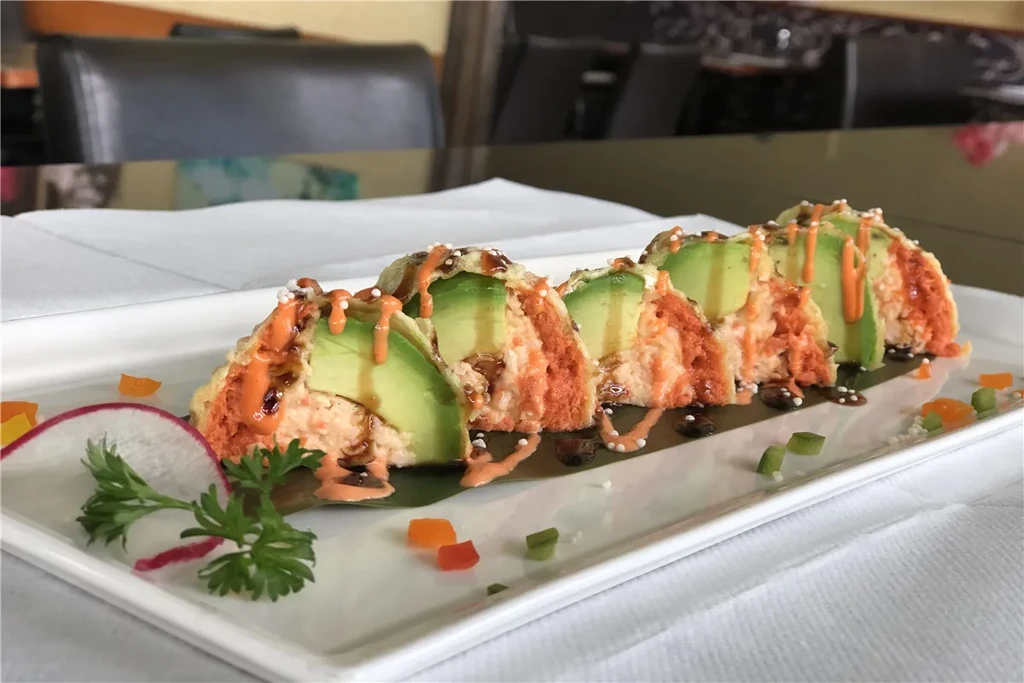 Crispy tempura sushi rolls with avocado, sauces, and plate garnish.