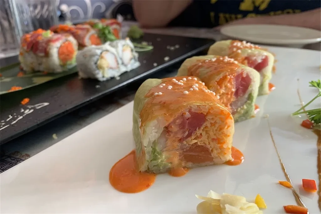 Assortment of sushi rolls on white and black plates.